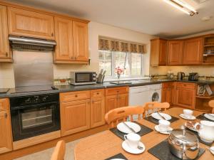 a kitchen with wooden cabinets and a table with chairs at Cefn Cottage in Llangurig