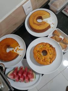 three plates of food with donuts and fruit on a counter at Pousada Chapada do Araripe in Araripina