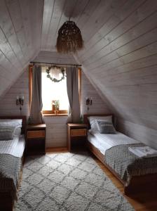 two beds in a attic room with a window at Siedlisko Gruszki Puszcza Białowieska in Narewka
