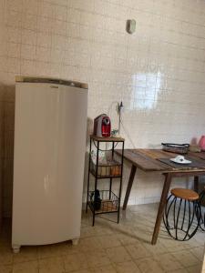 a kitchen with a table and a white refrigerator at Quarto COMPÔ 6 in São João del Rei
