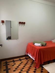 a room with a bed with a red blanket and a mirror at Quarto COMPÔ 6 in São João del Rei