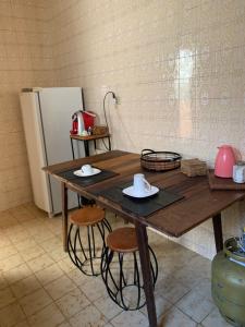 a wooden table with two stools and a refrigerator at Quarto COMPÔ 6 in São João del Rei