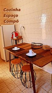 a wooden table in a kitchen with two stools at Quarto COMPÔ 6 in São João del Rei