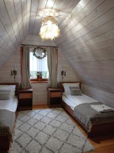Schlafzimmer im Dachgeschoss mit 2 Betten und einem Kronleuchter in der Unterkunft Siedlisko Gruszki Puszcza Białowieska in Narewka