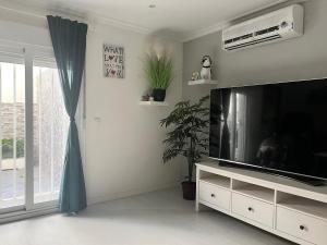 a living room with a large television and a window at Luminoso apartamento con precioso y amplio patio in Carabanchel Alto