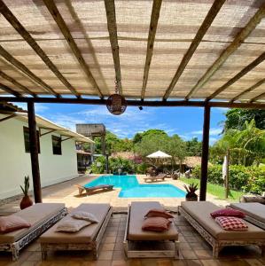 une terrasse avec 2 lits et une piscine dans l'établissement Pousada Tubarão, à Arraial d'Ajuda