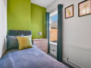 Dormitorio verde con cama y ventana en Entire townhouse in central Derby - with Garden!, en Derby