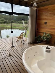 a bath tub on a wooden deck with a view of a lake at Aconchegante chalé com spa e hidromassagem in Bom Retiro