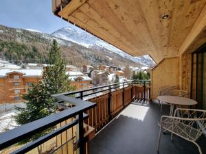 a balcony with a table and chairs and mountains at Riverside 2nd Floor North in Saas-Fee