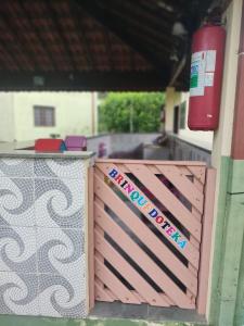 une porte en bois avec un panneau sur le côté du bâtiment dans l'établissement Pousada Porto Aventura -Chalés da Luci, à Peruíbe