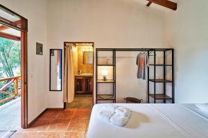 a bedroom with a white bed and a bathroom at Casa Calocita in Santa Teresa Beach