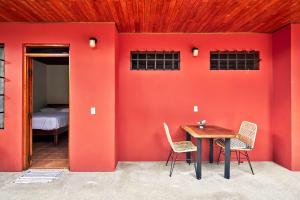a room with a red wall with a table and chairs at Casa Calocita in Santa Teresa Beach