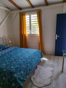 Un dormitorio con una cama azul y una ventana en Bungalow indépendant à Dalciat Baie-Mahault en Baie-Mahault