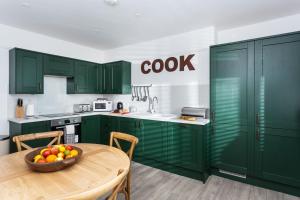 a kitchen with green cabinets and a bowl of fruit on a table at Godrevy in Landewednack
