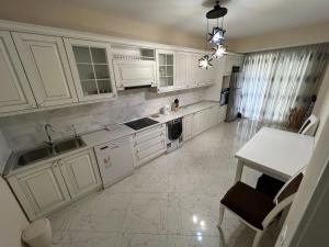 a kitchen with white cabinets and a sink and a table at Park Azure 11054 in Baku