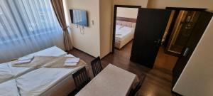 シュトゥーロヴォにあるElite Pensionのベッド、テーブル、窓が備わる客室です。