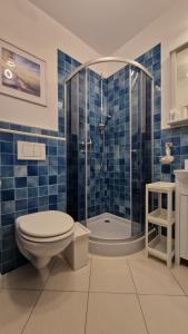 a blue tiled bathroom with a toilet and a shower at Apartament CALMA in Krynica Morska +10 photos