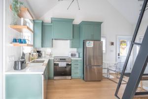 a kitchen with green cabinets and a stainless steel refrigerator at Stylish and Cozy Tiny House with King bed in Kitchener