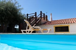 聖巴托洛梅烏迪梅西尼什的住宿－B&B Quinta da Romãzeira，一个带两把椅子的游泳池以及一座房子