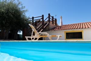 a swimming pool with two chairs and a house at B&B Quinta da Romãzeira in São Bartolomeu de Messines