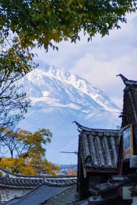 uma montanha coberta de neve em frente a um edifício em Old Town of Lijiang Meiliju Inn em Lijiang