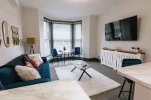 uma sala de estar com um sofá azul e uma mesa em GROVE HOUSE NO.07 - Luxury Apartment close to the Llandudno Beach em Llandudno