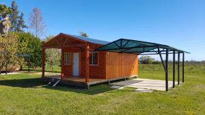 un pequeño edificio de madera con techo en un campo en Posada del Campo en San José