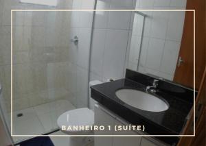 een badkamer met een wastafel, een toilet en een spiegel bij TH 3406 - Flat de Três Quartos in Governador Valadares