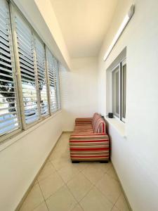 Rambam BEACH apartment في حيفا: غرفة بها كرسي احمر وبيضاء في غرفة بها نوافذ