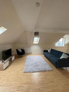 a living room with a blue couch and a television at Swindon City Center 2bed apartment with Parking and WiFi in Swindon