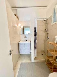 een witte badkamer met een wastafel en een douche bij Rambam BEACH apartment in Haifa