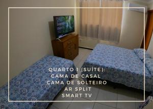 uma fotografia de um quarto com uma cama e uma televisão em TH 3406 - Flat de Três Quartos em Governador Valadares