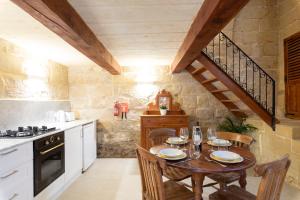 a kitchen with a wooden table and a wooden staircase at Razzett Ghasri in Għasri