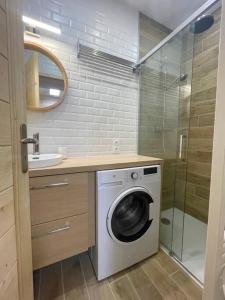 ein Badezimmer mit einer Waschmaschine und einem Waschbecken in der Unterkunft LE NID in Cauterets