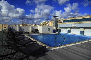 a swimming pool on top of a building with chairs at Sliema Tigne Suites in Sliema