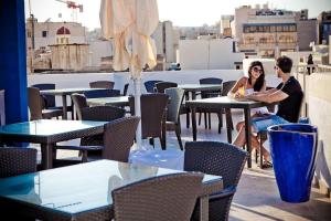 a man and woman sitting at tables on a roof at Sliema Tigne Suites in Sliema