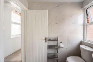 ein weißes Bad mit einem WC und einem Fenster in der Unterkunft Maybury Maison in Woking