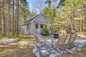 a tiny house in the woods with chairs and a fireplace at Maine Lodging Near Acadia National Park! in Bernard