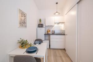 a small white kitchen with a white table and chairs at Studio chic proche aéroport & centre-ville in Charleroi +32 photos