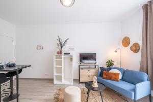 a living room with a blue couch and a tv at Studio chic proche aéroport & centre-ville in Charleroi