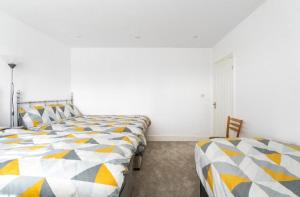 2 Betten in einem Zimmer mit weißen Wänden in der Unterkunft Maybury Maison in Woking