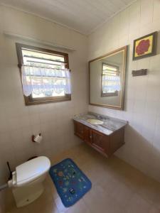 a bathroom with a toilet and a sink and a mirror at Chalé Aconchegante 2km do Centrinho in Campos do Jordão