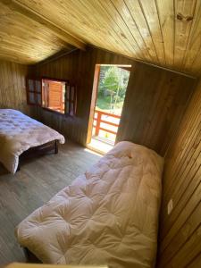 a large bed in a wooden room with a window at Chalé Aconchegante 2km do Centrinho in Campos do Jordão