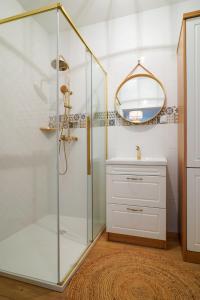 a bathroom with a shower with a sink and a mirror at Apartament Gdańsk Premium Porto in Gdańsk