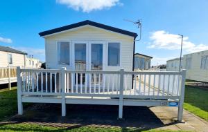 a small white house with a white fence at Cosy holiday home at Romney Sands in New Romney