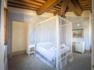 een slaapkamer met een wit bed en een baldakijn bij Borgo Pian di Sala in San Gimignano