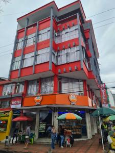 Ein rotes Gebäude mit Leuten, die davor stehen. in der Unterkunft Hotel las Corocoras del llano in Villavicencio