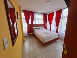 ein kleines Schlafzimmer mit roten Vorhängen und einem Bett in einem Zimmer in der Unterkunft Hotel las Corocoras del llano in Villavicencio + 12 Fotos