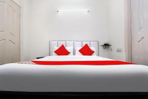 a large white bed with red pillows on it at Collection O Ramji 7 Grand Near Tdi Mall in New Delhi