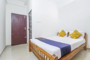 a bedroom with a bed with yellow and blue pillows at SPOT ON Rohini Inn Kadampuzha in Kottakkal